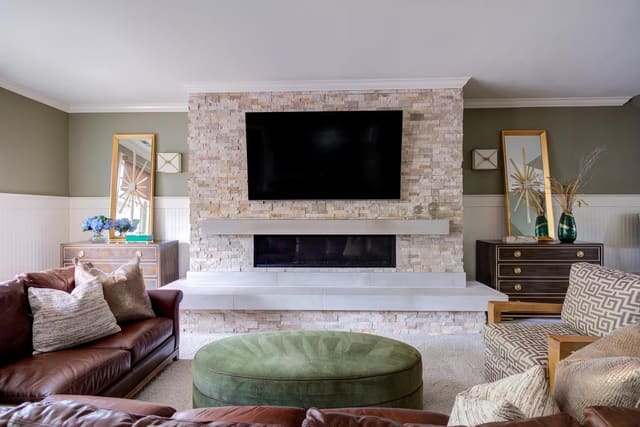 Lillian August matching chests behind a large leather sectional with an upholstered ottoman.