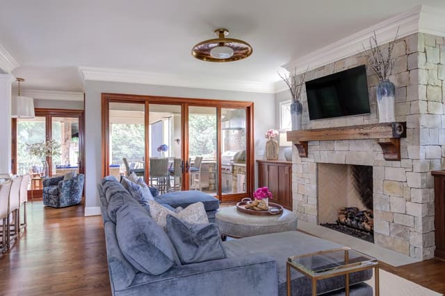 Large blue sectional and ottoman facing a stone fireplace.
