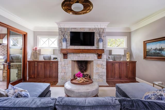 Large blue sectional and ottoman facing a stone fireplace.