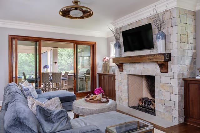 Large blue sectional and ottoman facing a stone fireplace.