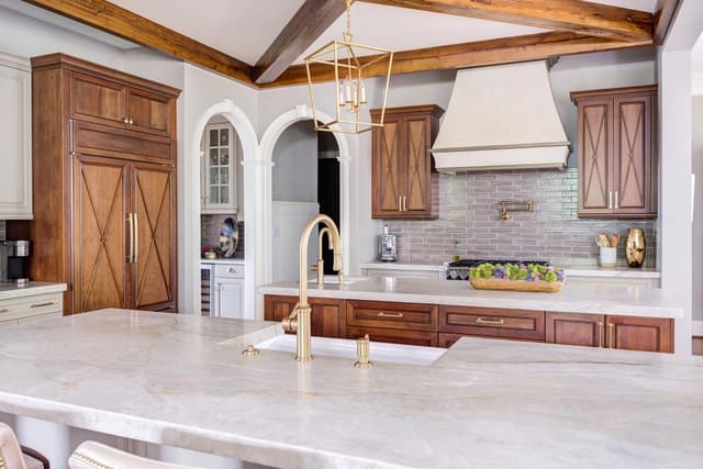 Open concept kitchen with two marble islands contrasting with the natural wood finished cabinets.