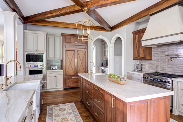 Open concept kitchen with two marble islands contrasting with the natural wood finished cabinets.