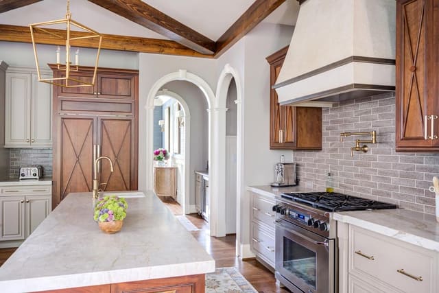 Open concept kitchen with two marble islands contrasting with the natural wood finished cabinets.