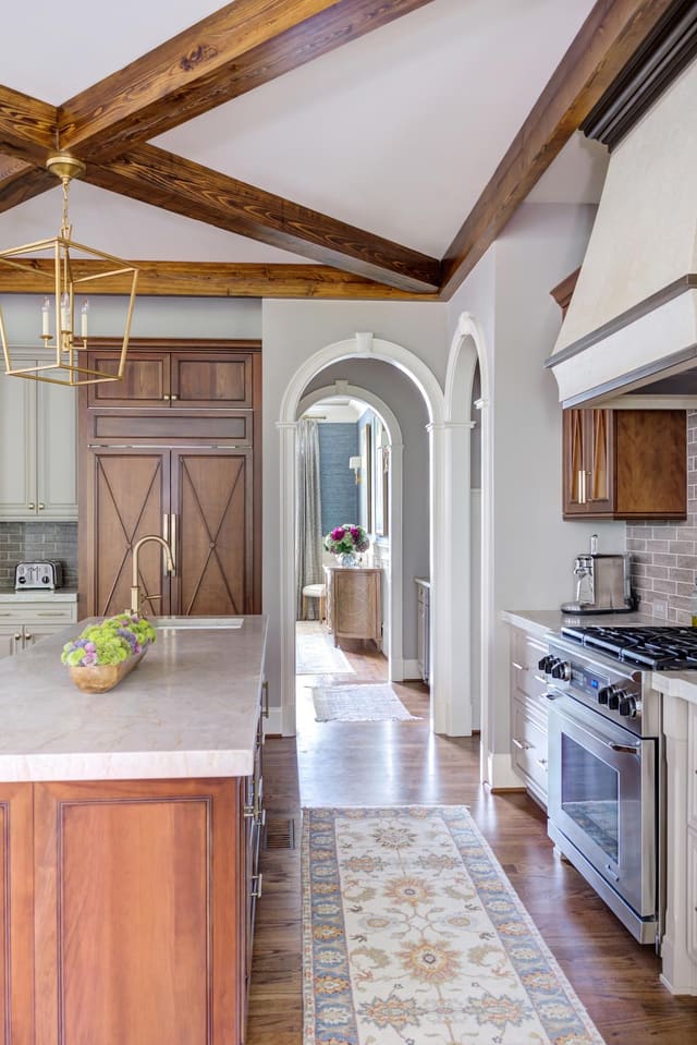 Open concept kitchen with two marble islands contrasting with the natural wood finished cabinets.