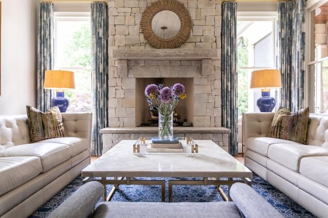 Two white leather tufted sofas in the sitting room split between a marble cocktail table.