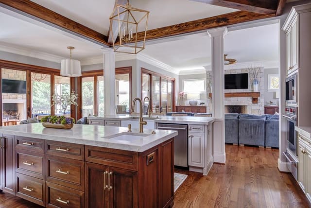 Open concept kitchen with two marble islands contrasting with the natural wood finished cabinets.