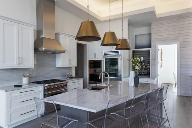 Kitchen of Apex Home featuring granite backsplash, brass pendants and acrylic barstools