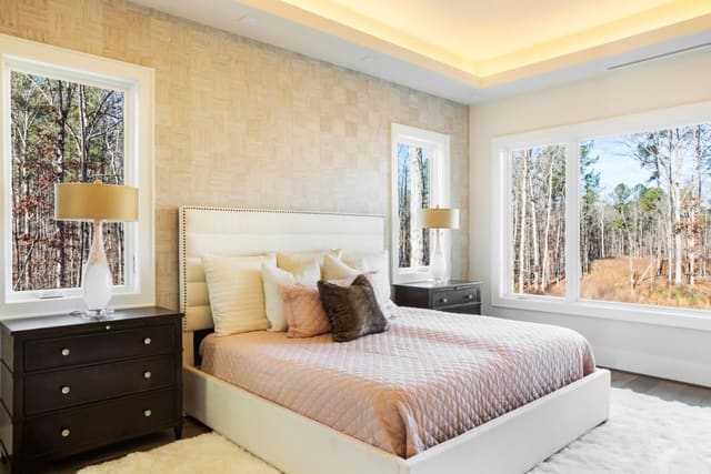 Master Bedroom of Apex home with wallpapered accent wall and tray ceiling.