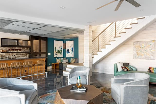 Basement Entertainment Room of Apex home with stained concrete flooring, swivel chairs, funky coffee table and leather social sofa.