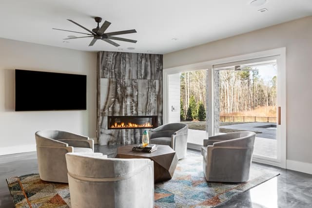Basement Entertainment Room of Apex home featuring seating area with linear, granite surround fireplace, swivel chairs, funky coffee table and colorful rug