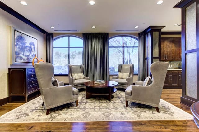 Reception area of Cary Bank with 4 leather chairs surrounding round cocktail table on wool rug.