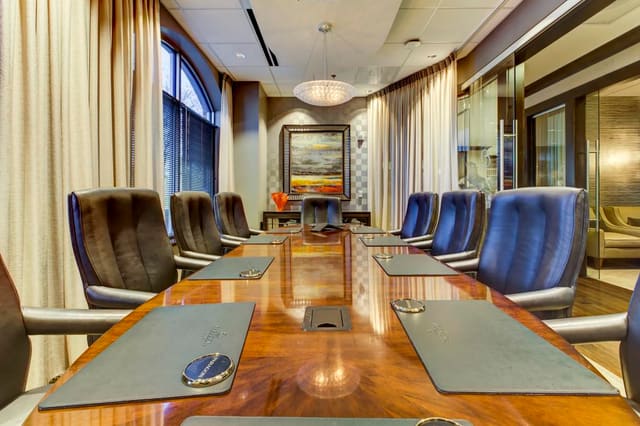 Conference Room of Cary bank with custom conference table, leather executive chairs, hanging lights, mirrored credenzas, original artwork and sheer panels on windows and interior wall.