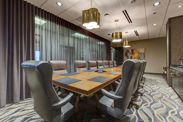2nd Conference Room of Cary Bank with brass pendant lighting over custom maple and gold leaf conference table with leather executive chairs.