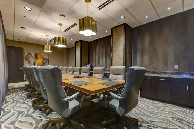 2nd Conference Room of Cary Bank with brass pendant lighting over custom maple and gold leaf conference table with leather executive chairs.