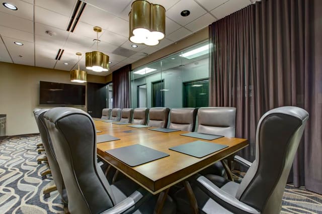 2nd Conference Room of Cary Bank with brass pendant lighting over custom maple and gold leaf conference table with leather executive chairs.  Custom sheers over interior windows.