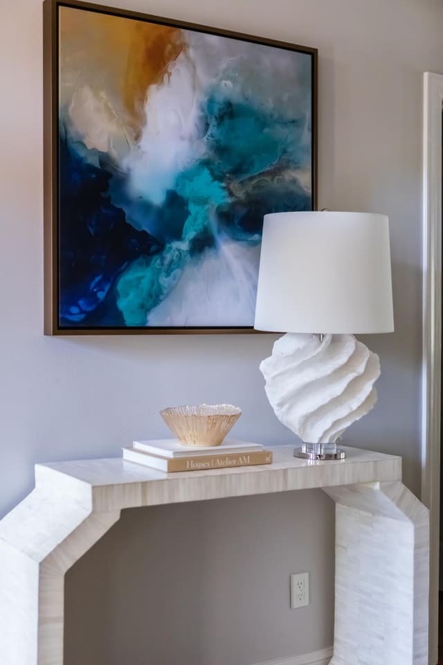 Foyer of Cary home featuring natural bone console table, cream spiral lamp and abstract artwork