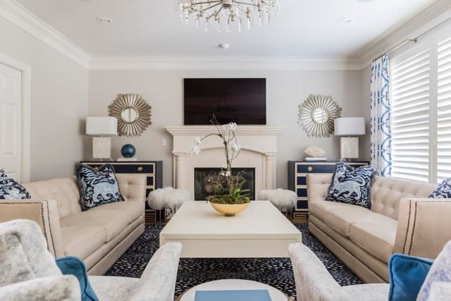 Family Room featuring navy antelope rug, twin leather sofas, custom drapery, and pair of chest flanking fireplace with matching lamps and mirrors