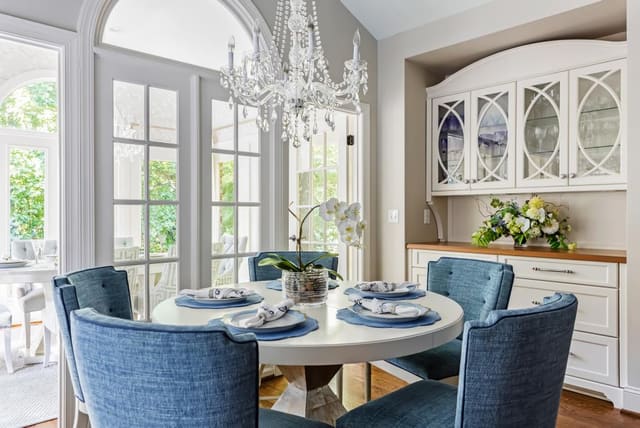 Breakfast Nook featuring wine bar, white table top with silver leaf base, and blue upholstered dining chairs with contrast welt