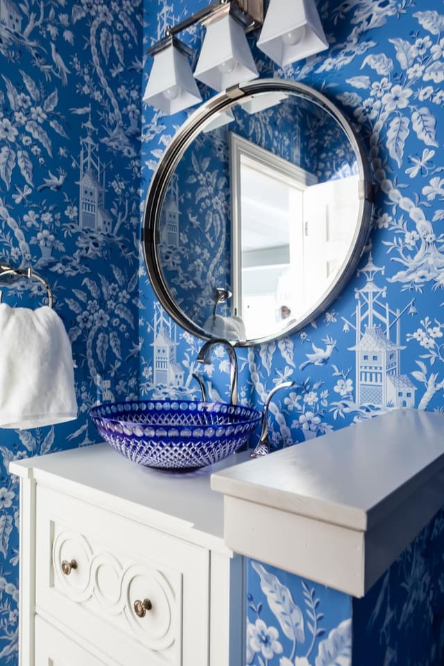 Formal Powder Room with white vanity, polished nickel light, and blue print wallpaper