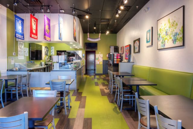 Interior of Diced Restaurant in Cary with colorful LVT Flooring, Green Laminate Banquettes, Black Tables, and Silver Chairs