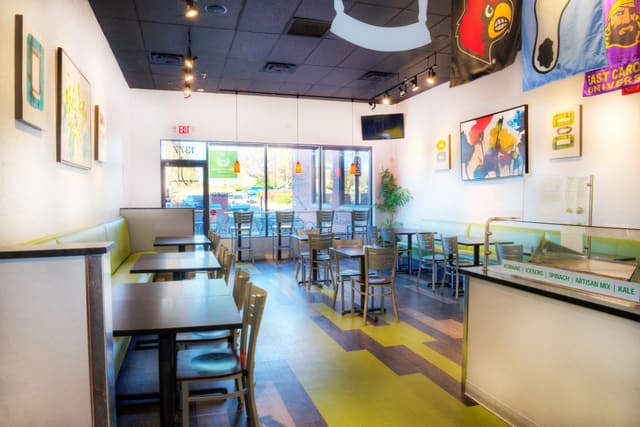 Interior of Diced Restaurant in Cary with colorful LVT Flooring, colorful artwork, Green Laminate Banquettes, Black Tables, and Silver Chairs