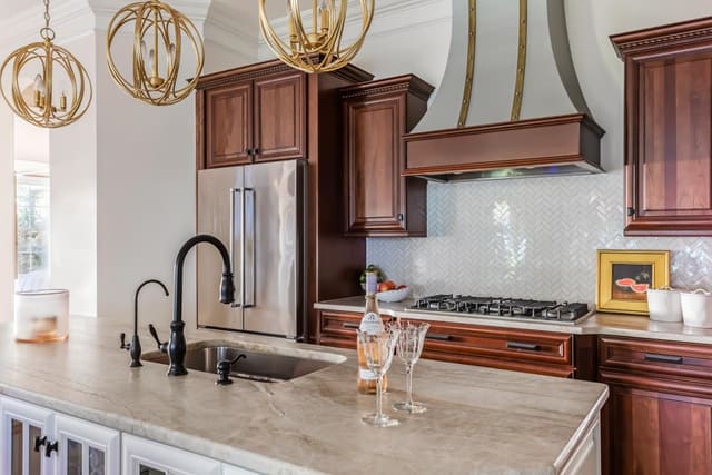 Remodeled Kitchen, keeping dark wood cabinets and adding white accents, new leathered countertops, brass lighting, and custom range hood.