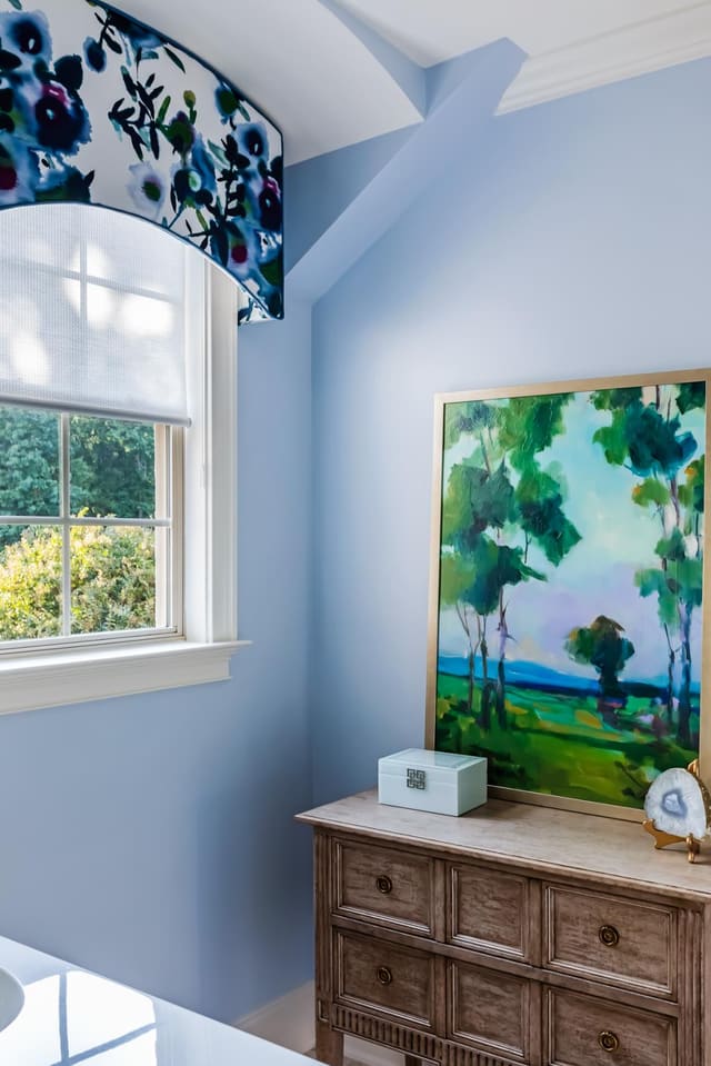 Serene blue bathroom with floral cornice and watercolor artwork.