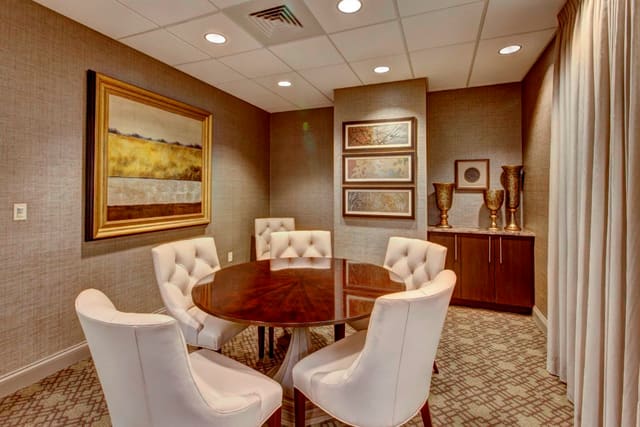 Executive Conference Room at Paragon Bank with beautiful wallpaper, tufted leather dining chairs, dining table, and custom drapery