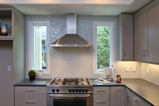 Kitchen in Downtown Raleigh home with white subway tile backsplash and stainless steel range and hood