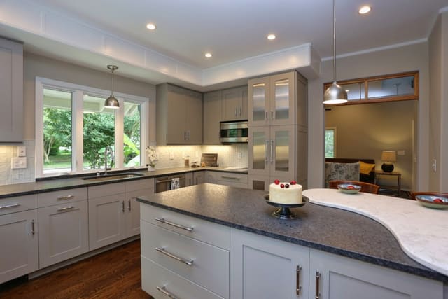 Kitchen in Downtown Raleigh home with white subway tile backsplash, painted cabinets, and island with contrasting stone bumpout bar