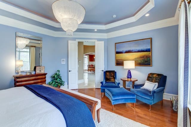 Master Bedroom with blue velvet chairs and two-tier chandelier