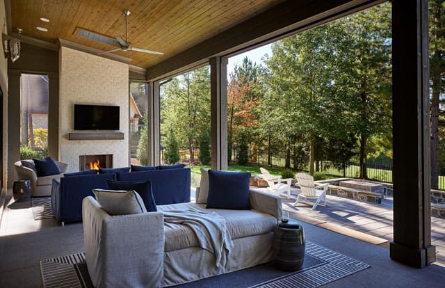 Covered porch of Wake Forest home showing outdoor fireplace and upholstered furniture