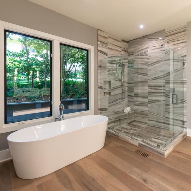 Standalone bathtub with marble shower.