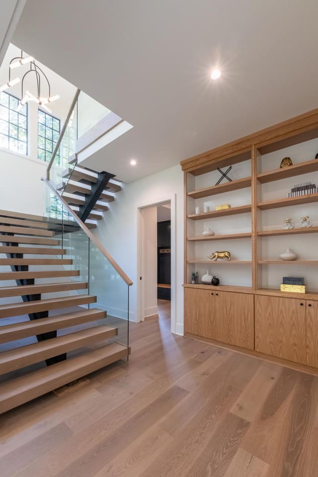 Floating staircase overlooking decorated bookshelves.