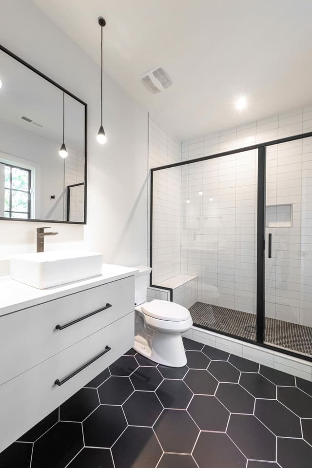 Black honeycomb tile accompanied by black and white details in this half bathroom.