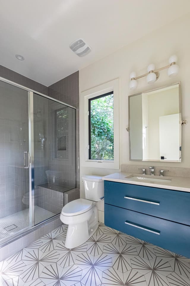 Bathroom with blue cabinets and a unique tile floor.