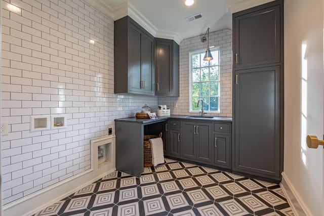 Laundry Room in Raleigh home with grey cabinets and funky tile