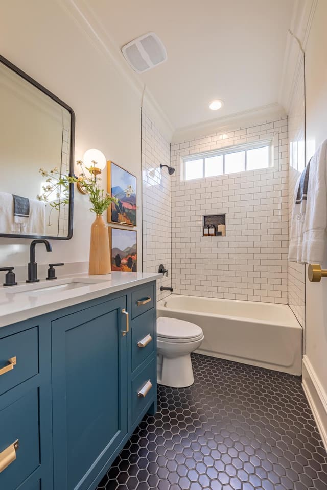 Guest Bathroom with teal vanity and black tile.