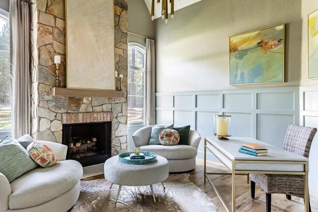 Study with white and brass desk and cozy chairs flanking fireplace.