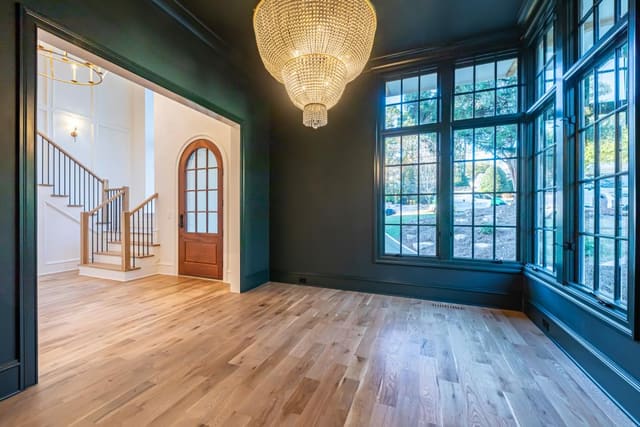 Study with dark green walls and trim and Visual Comfort Chandelier
