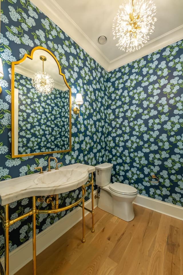 Half bath with floral wallpaper and gold hardware.