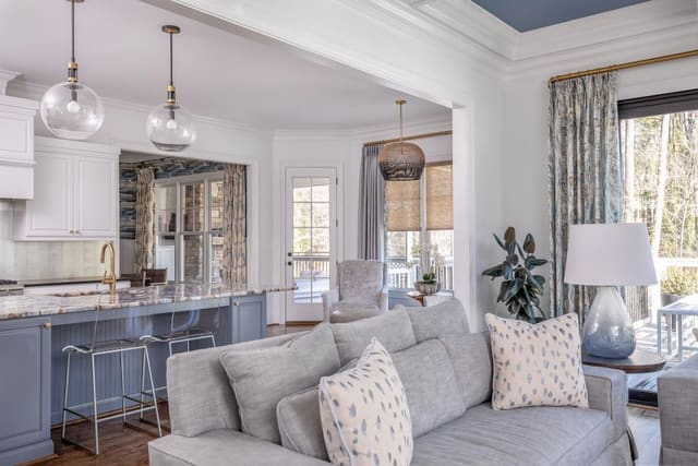 Open-concept kitchen and living room with blue cabinetry, marble countertops, and neutral tones.