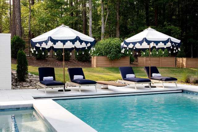 Outdoor pool area with four lounge chairs and umbrellas.