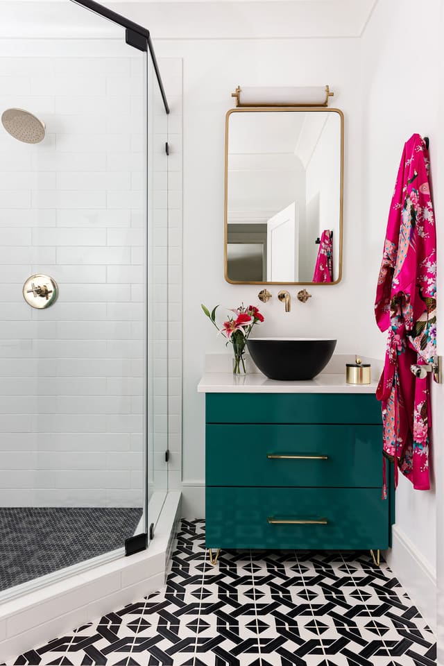 Basement bathroom with a teal cabinet and black and white tile.