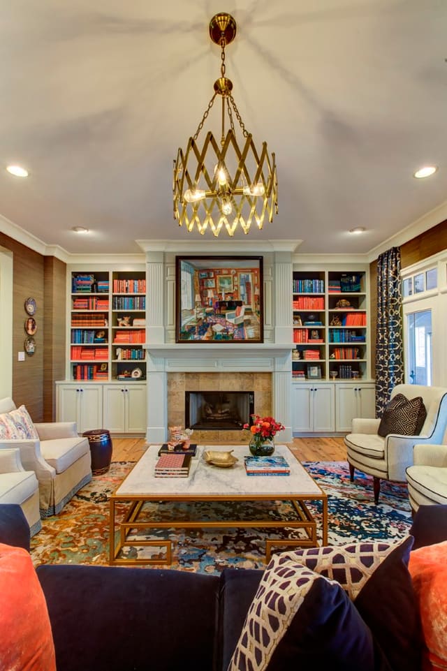 Living Room with custom built-ins with color coordinated books, coffee table, chairs, sofa, colorful rug