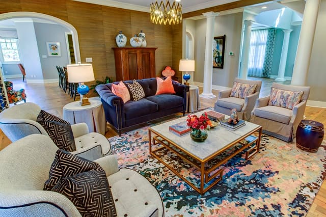 Living Room with coordinating upholstery, colorful rug, brass light fixture, and stone top cocktail table