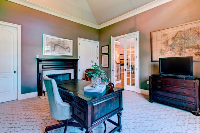 Home Office with floating desk, upholstered desk chair, framed maps, and fireplace