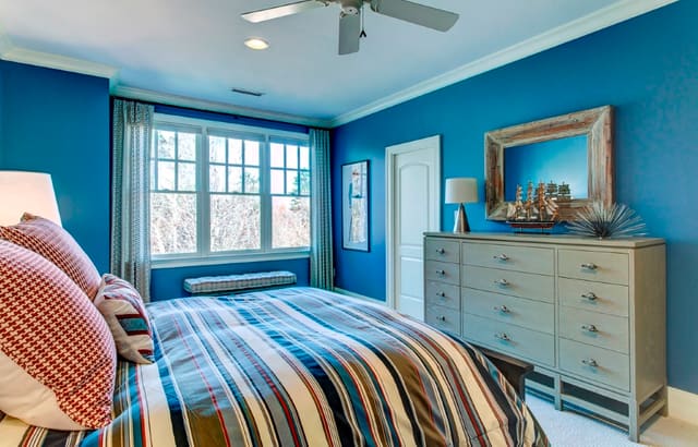 Nautical Themed Boy's Bedroom with blue walls, red and blue bedding, and custom window treatments