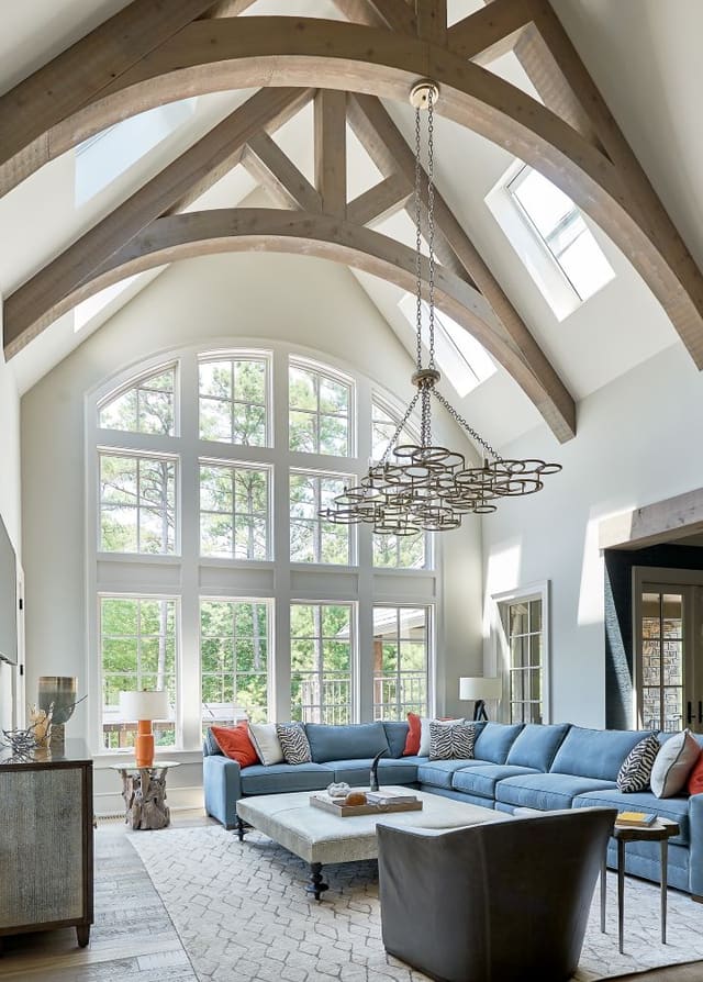 Family Room in N. Raleigh Model Home with blue sectional, large ottoman, large hanging chandelier and plush rug