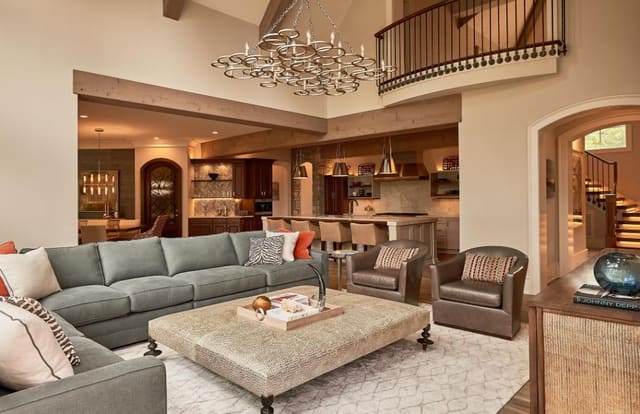 Family Room in N. Raleigh Model Home with blue sectional, large ottoman, large hanging chandelier and plush rug
